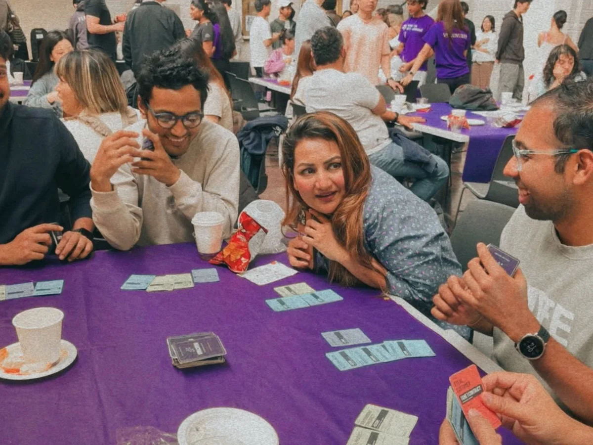 Players holding UNICORN cards around a purple table during a real prototype playtest